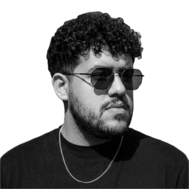 Retrato de Micael Marques, de cabelo cacheado, barba e óculos escuros.